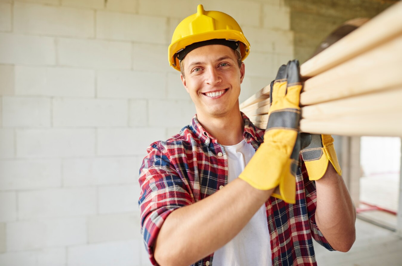 Молодой плотник держит в руках деревянные доски