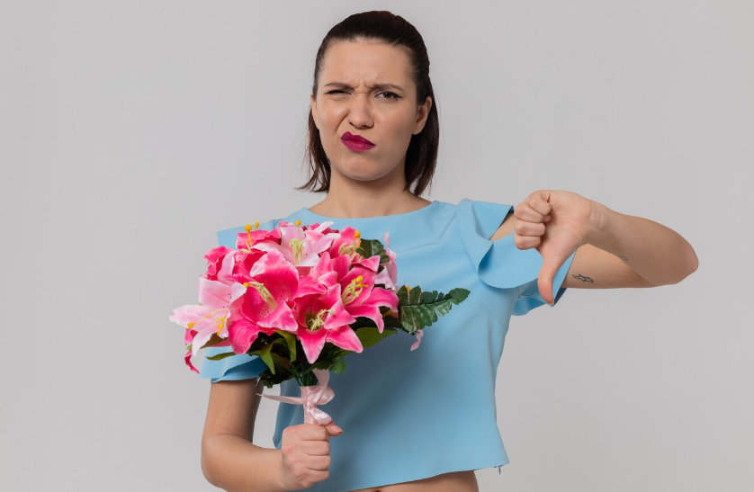 Недовольная молодая девушка с букетом цветов в руках